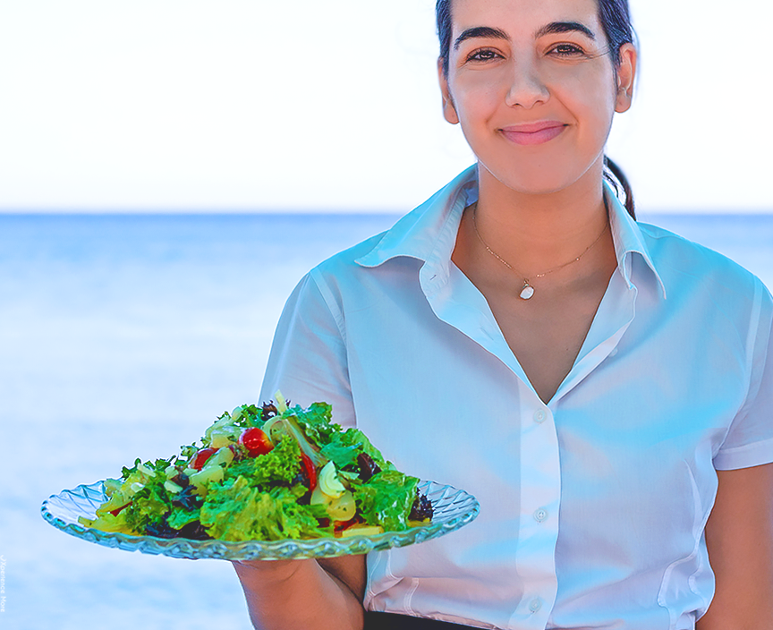 A server holding a plate with a salad at Zorbas Seaside Restaurant in Ierapetra