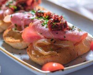 A bruschetta with pork and tomatoes