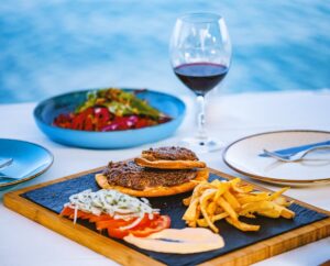 Kebab served on Pita bread with fresh tomatoes, crispy friesand sauce on ablack plate