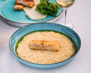 a blue plate with risotto with a fish filet